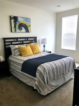 a bedroom with a bed with a striped comforter and yellow pillows