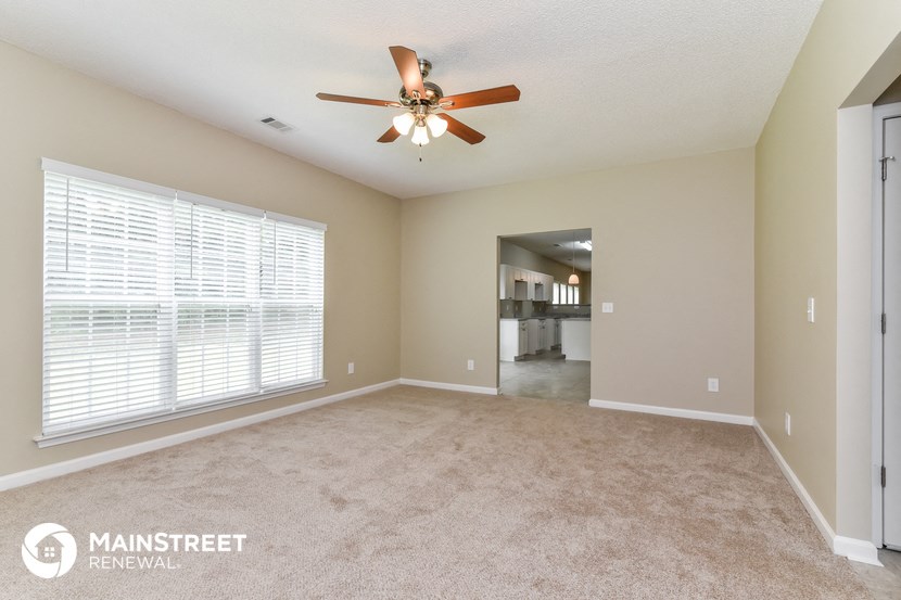 an empty living room with a ceiling fan and a large window
