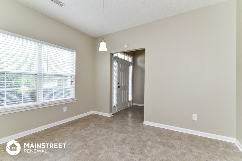 the living room of an apartment with a large window and a door to a hallway