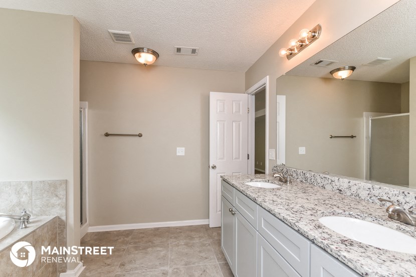 the master bathroom has dual sinks and a large mirror