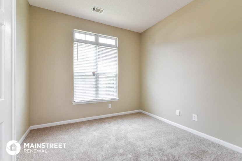 a bedroom with a carpeted floor and a window