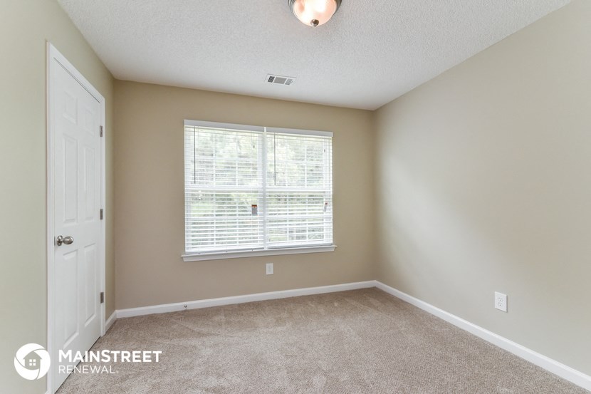 the upstairs bedroom has a large window and carpeted flooring