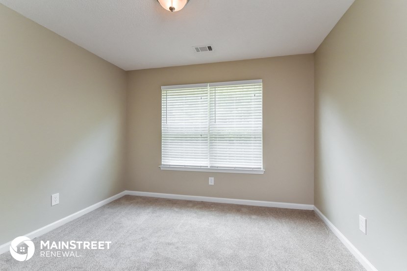 a white carpeted room with a window and a window sill