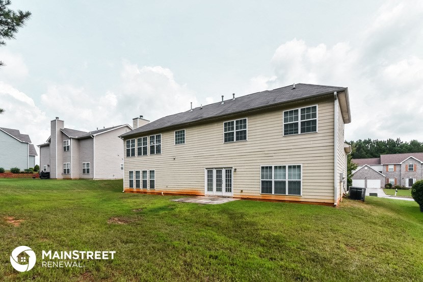 a white house with a wooden deck and a grass yard