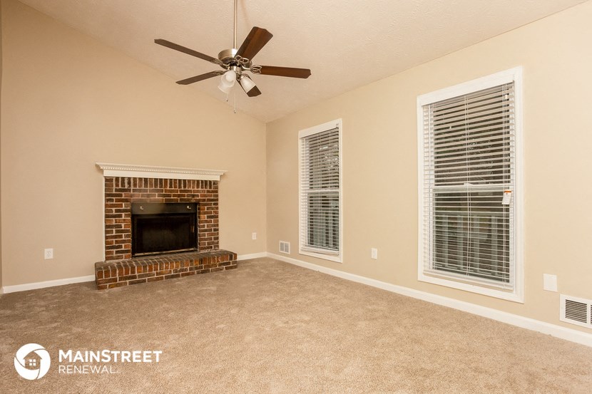 a living room with a fireplace and a ceiling fan