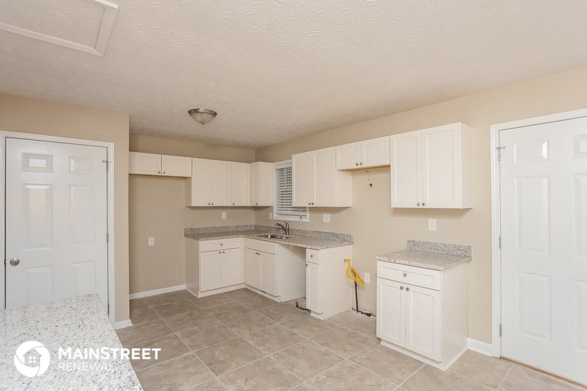 a kitchen with white cabinets and tile flooring and white appliances