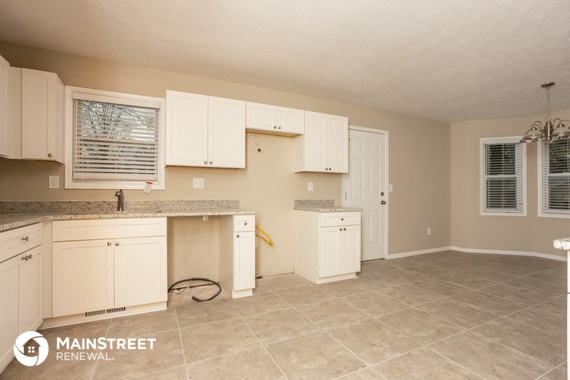 a kitchen with white cabinets and tiled floors and a counter top