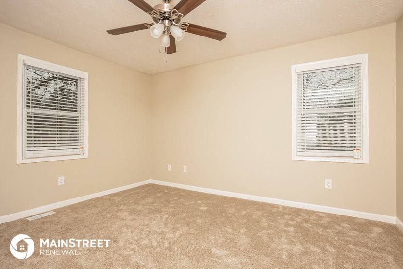 the master bedroom has carpeted floors and a ceiling fan