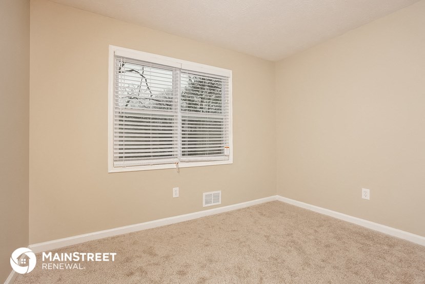 the upstairs bedroom has a large window and carpeted flooring