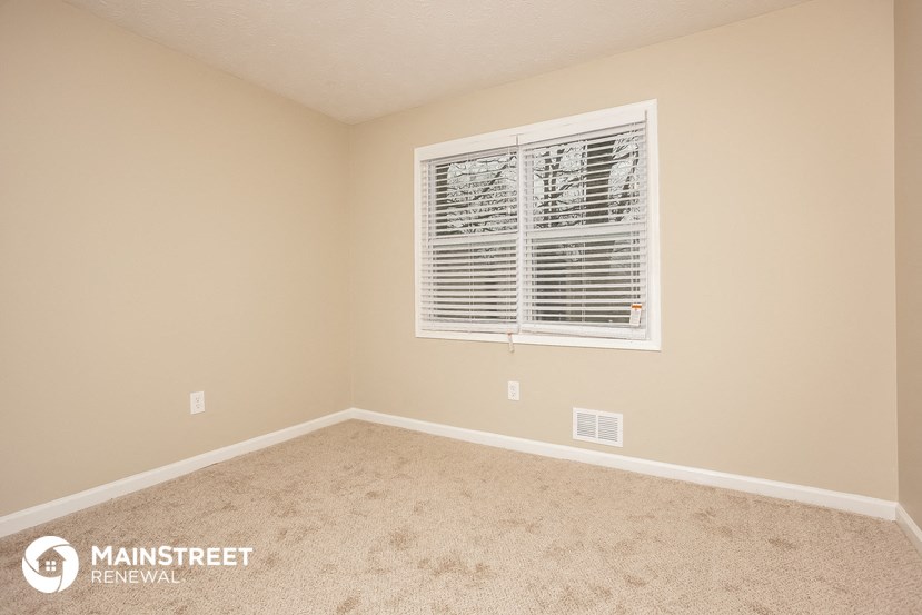 a bedroom with a window and a carpeted floor