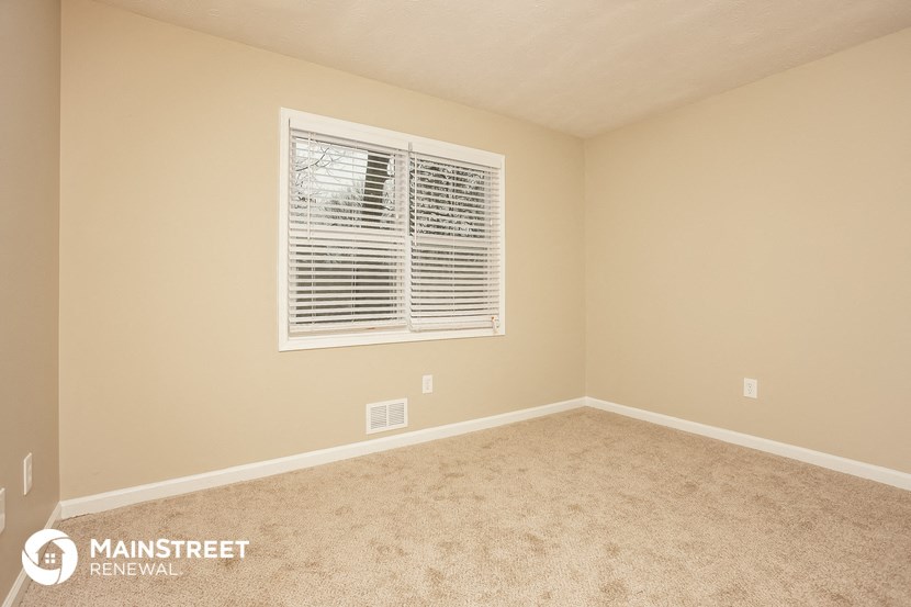 the upstairs bedroom has a large window and carpeted flooring
