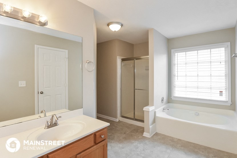the master bathroom has a large mirror and a tub and shower