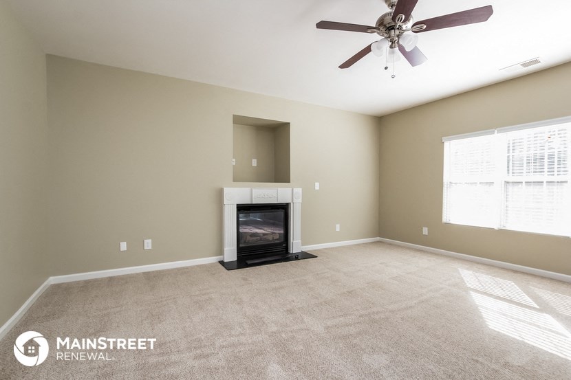 a living room with a fireplace and a ceiling fan