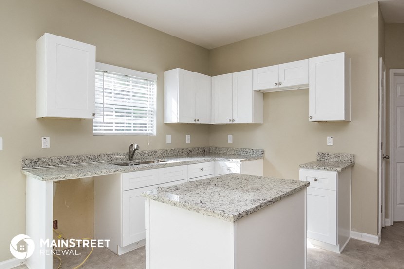a kitchen with white cabinets and granite counter tops