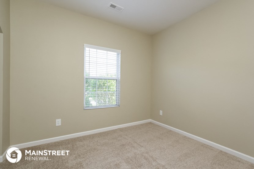 a spacious room with carpet and a window