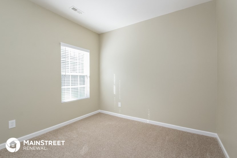 the upstairs bedroom has a carpeted floor and a window