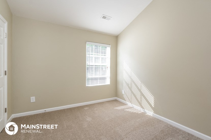the spacious living room has carpeted floors and a large window