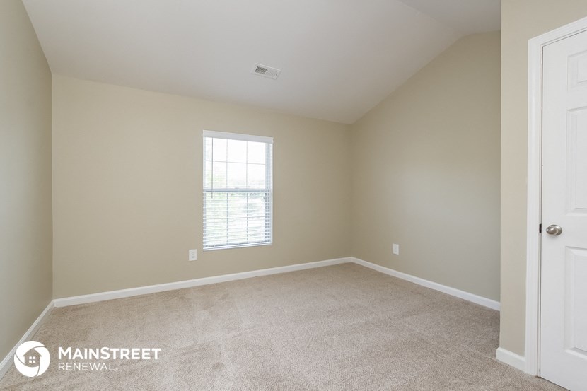a bedroom with a carpeted floor and a window
