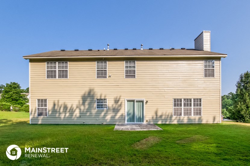 a small yellow house with a green lawn and a blue sky