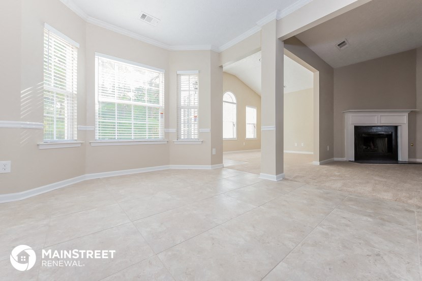 an empty living room with a fireplace and tile flooring