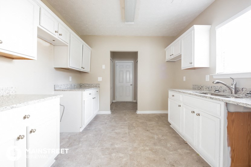 a white kitchen with white cabinets and a white door