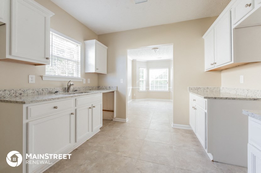a large kitchen with white cabinets and marble counter tops
