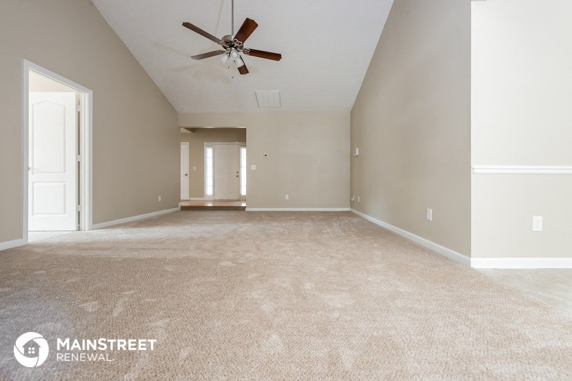 the spacious living room with carpet and ceiling fan