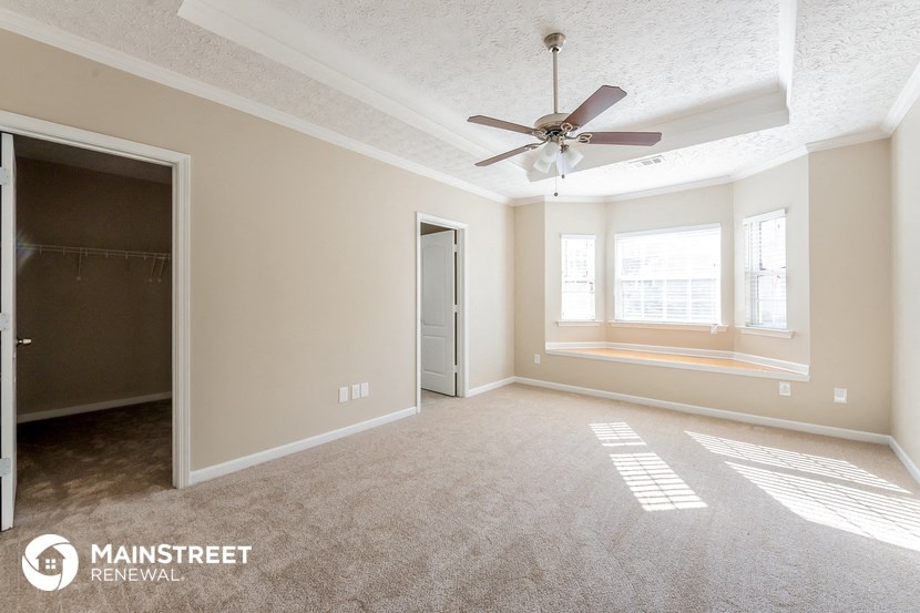 an empty living room with a ceiling fan and a window
