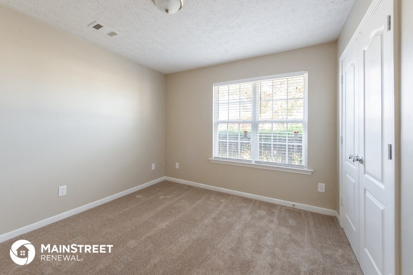 a bedroom with carpet and a large window