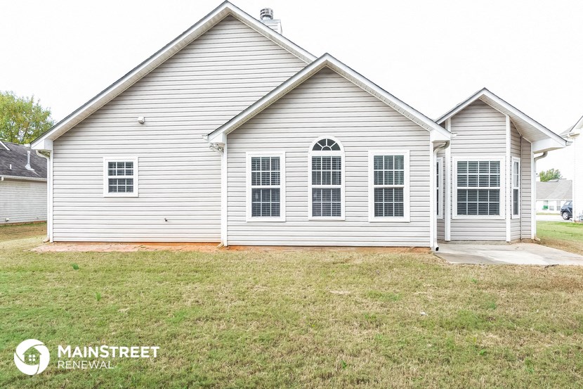 the front of a white house with a lawn in front of it