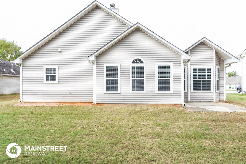 the front of a white house with a lawn in front of it