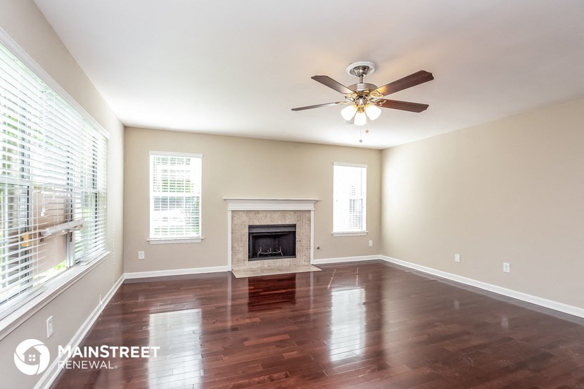 an empty living room with a fireplace and a ceiling fan