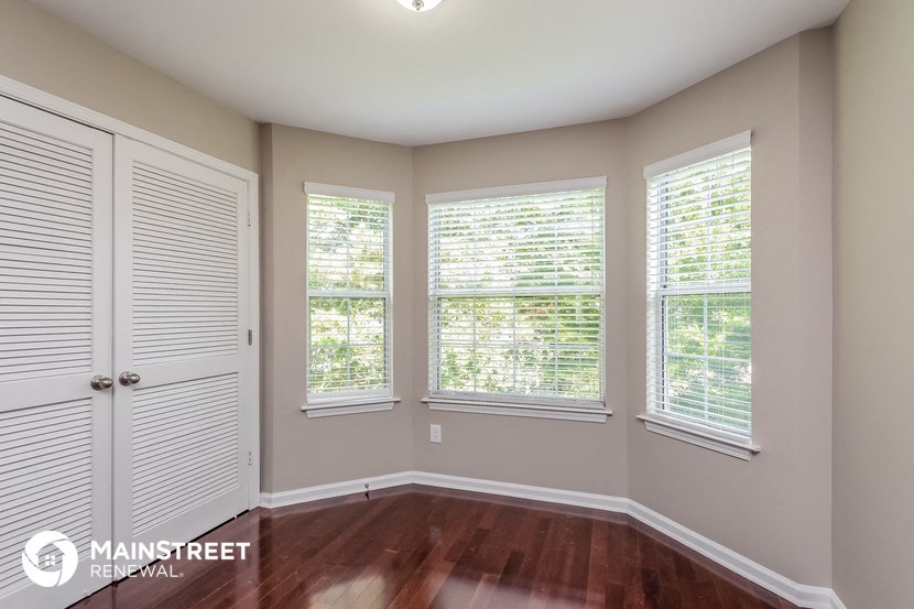 the master bedroom has a large window and wood flooring