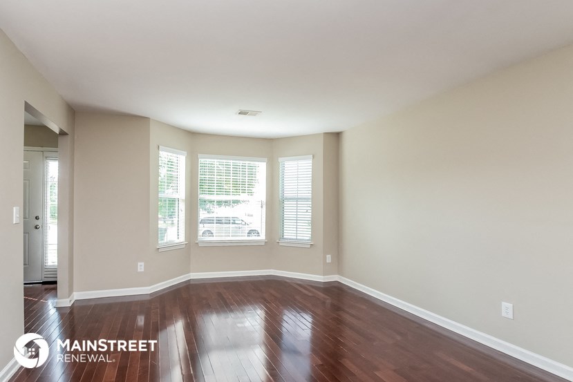 the living room with hardwood floors and large windows