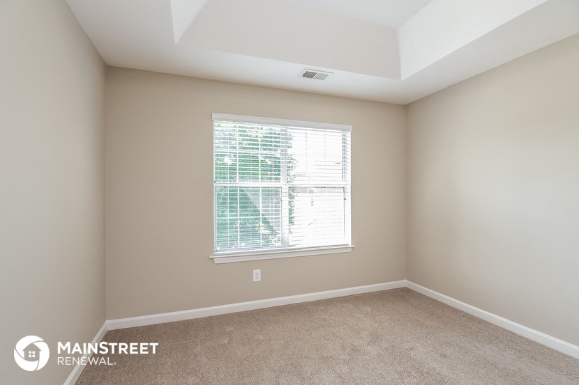a bedroom with a large window and a carpeted floor