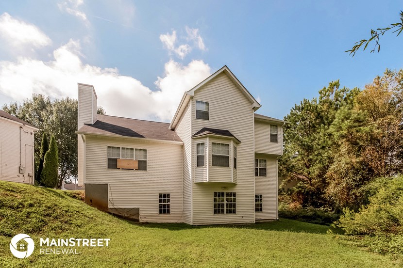 a white house on a hill with a grassy yard