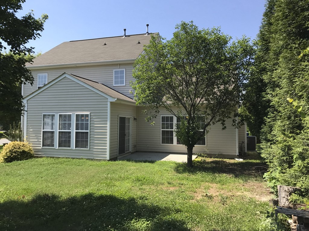 the front of a white house with a lawn and trees