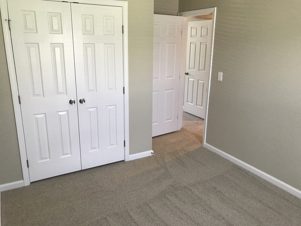 a bedroom with two closets and a carpeted floor