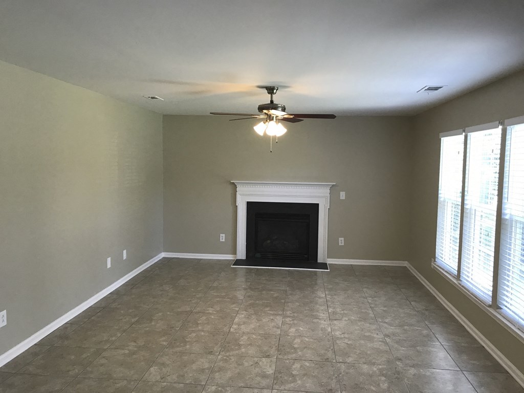 an empty living room with a fireplace and a ceiling fan