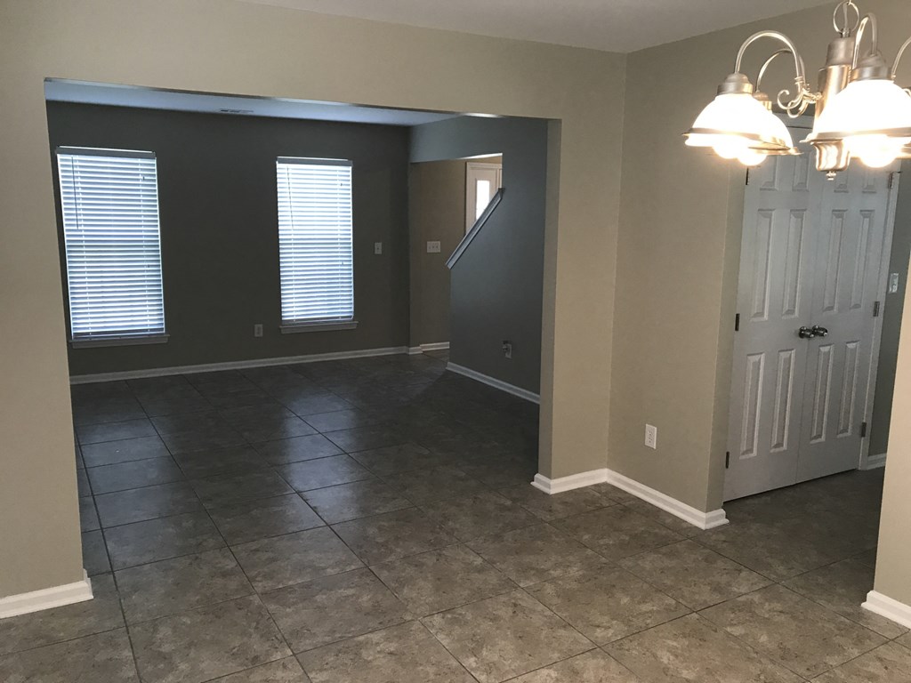 an empty living room with a door and a staircase
