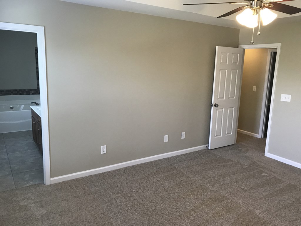 a living room with a carpeted floor and a door to a bathroom