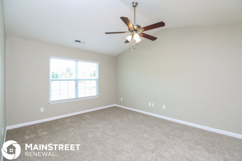 the master bedroom has a carpeted floor and a ceiling fan