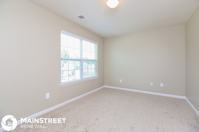 a bedroom with a carpeted floor and a large window