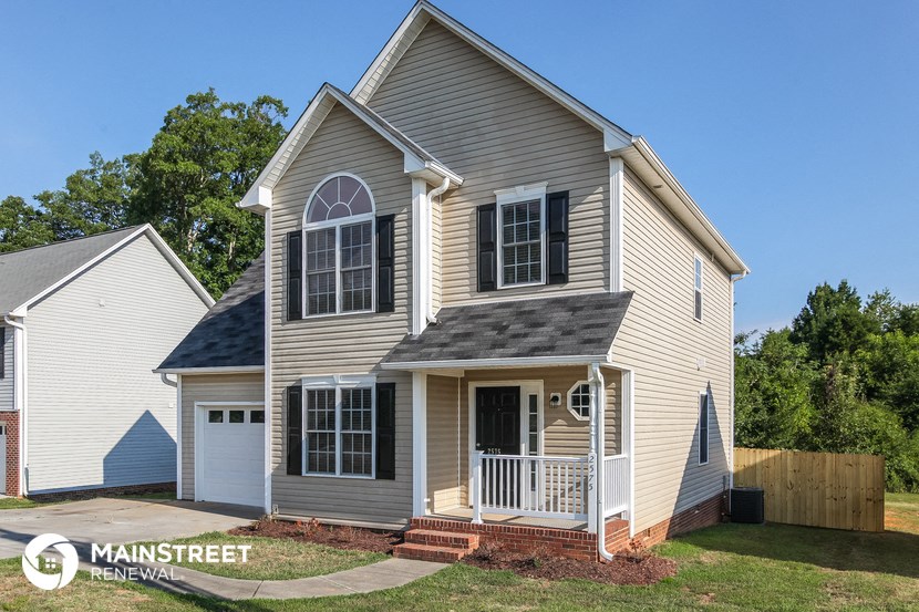 the front of a house with a lawn and a fence