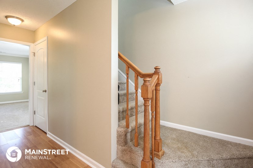 the landing of a staircase in a home with white walls and wood floors