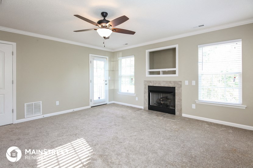 an empty living room with a ceiling fan and a fireplace