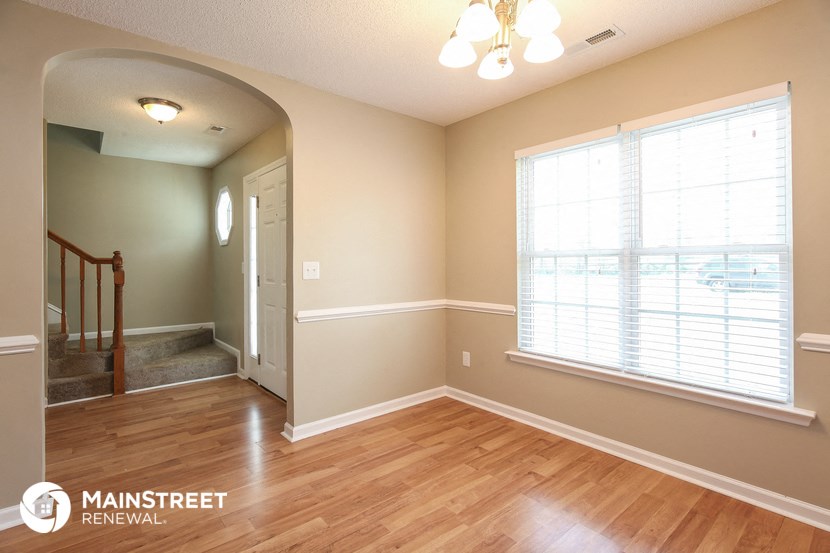 the living room and dining room of a home with wood floors and a large window