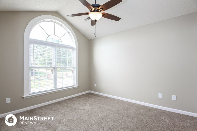 an empty room with a ceiling fan and a large window