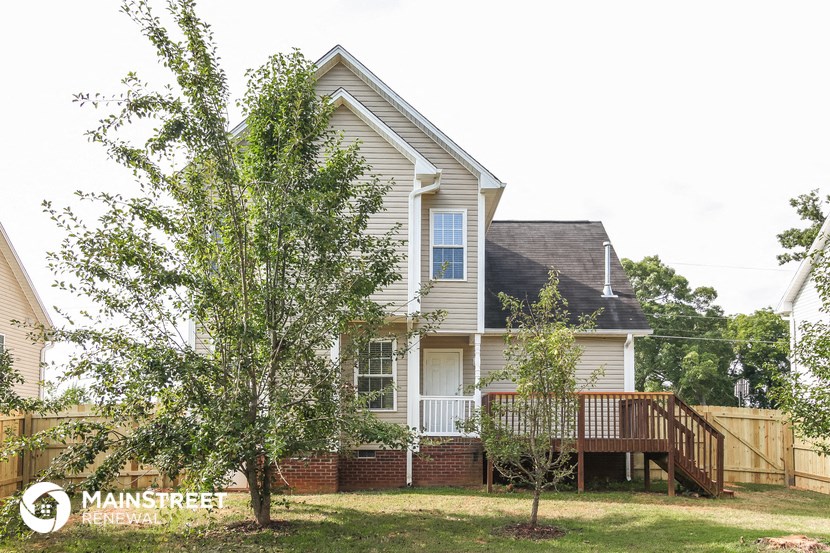 a house with a deck and trees in front of it