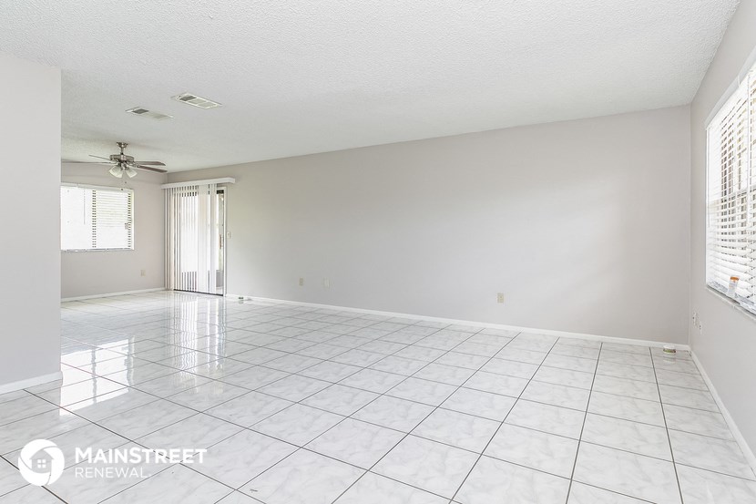 a spacious living room with white tile flooring and white walls